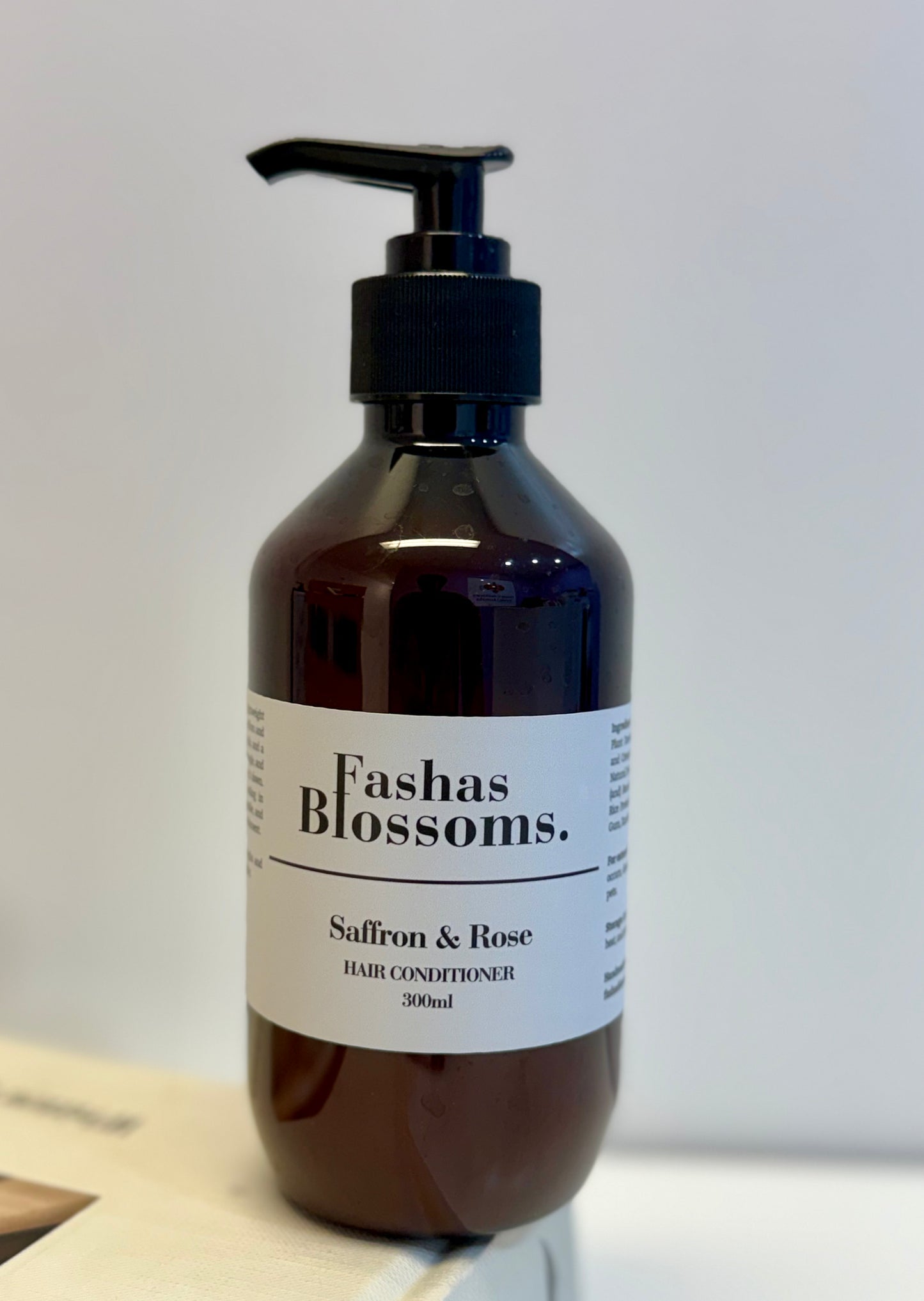 Brown bottle of Fashas Blossoms Saffron & Rose hair conditioner on a light background