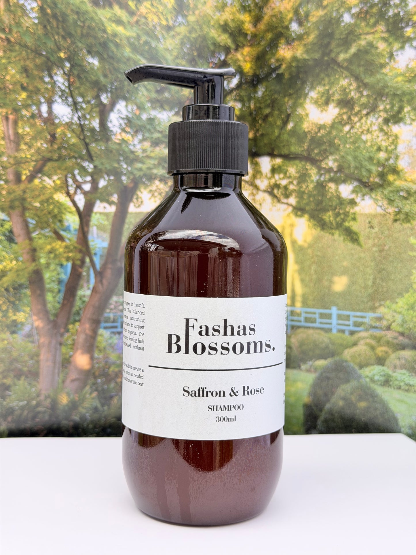 Bottle of Fashas Blossoms Saffron & Rose shampoo with a scenic background