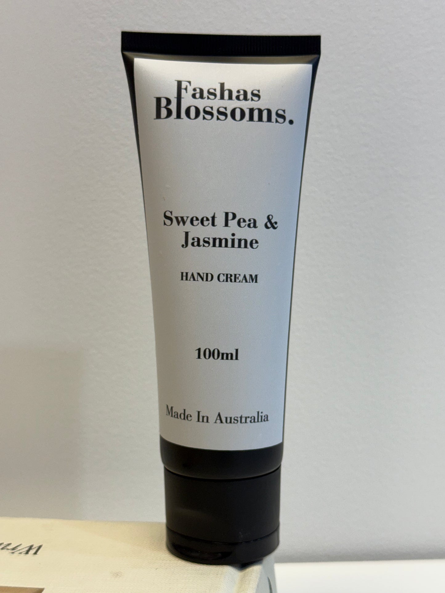 Hand cream tube labeled 'Fashas Blossoms Sweet Pea & Jasmine' on a neutral background