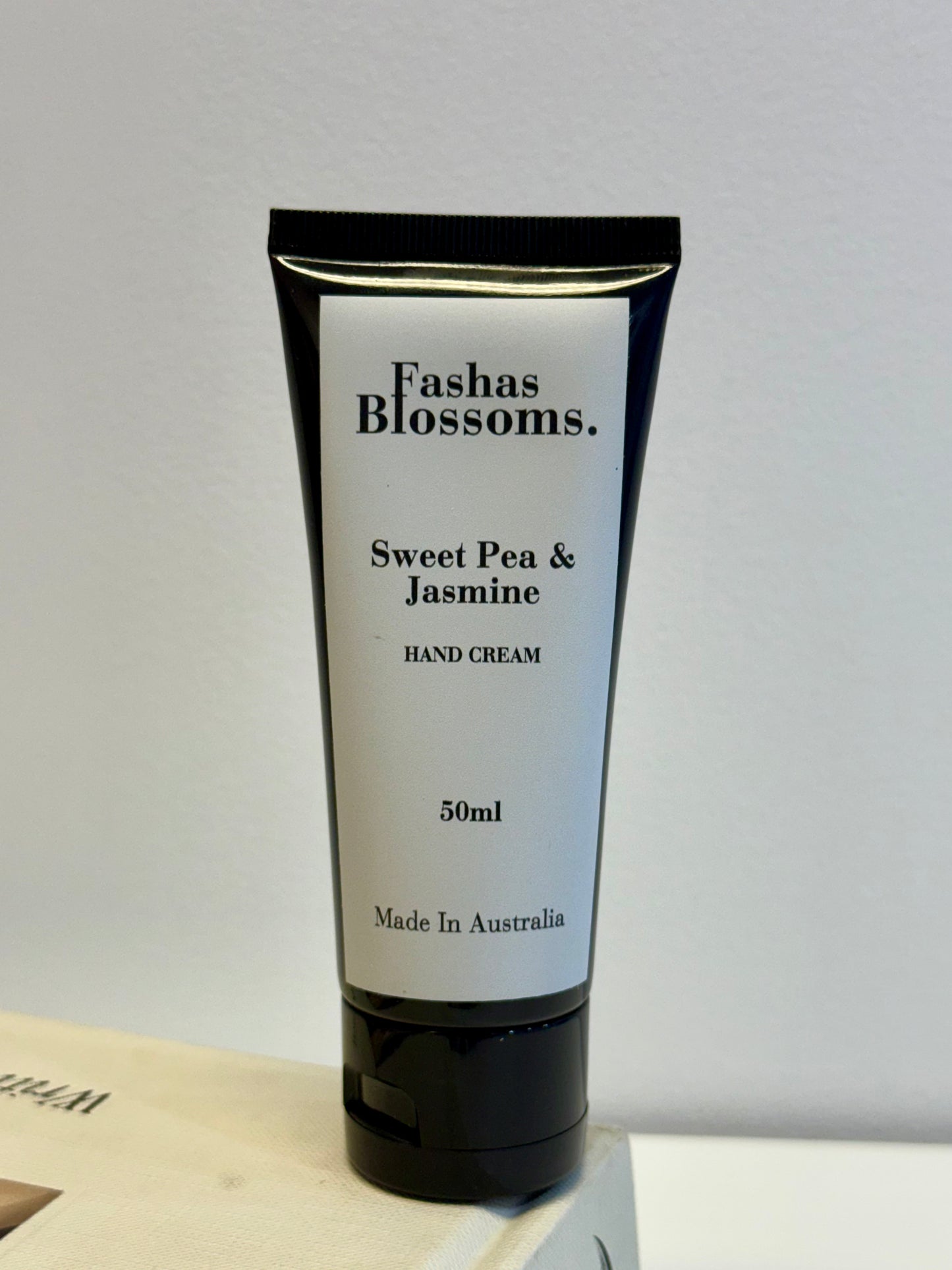 Hand cream tube labeled 'Fashas Blossoms Sweet Pea & Jasmine' on a light gray background