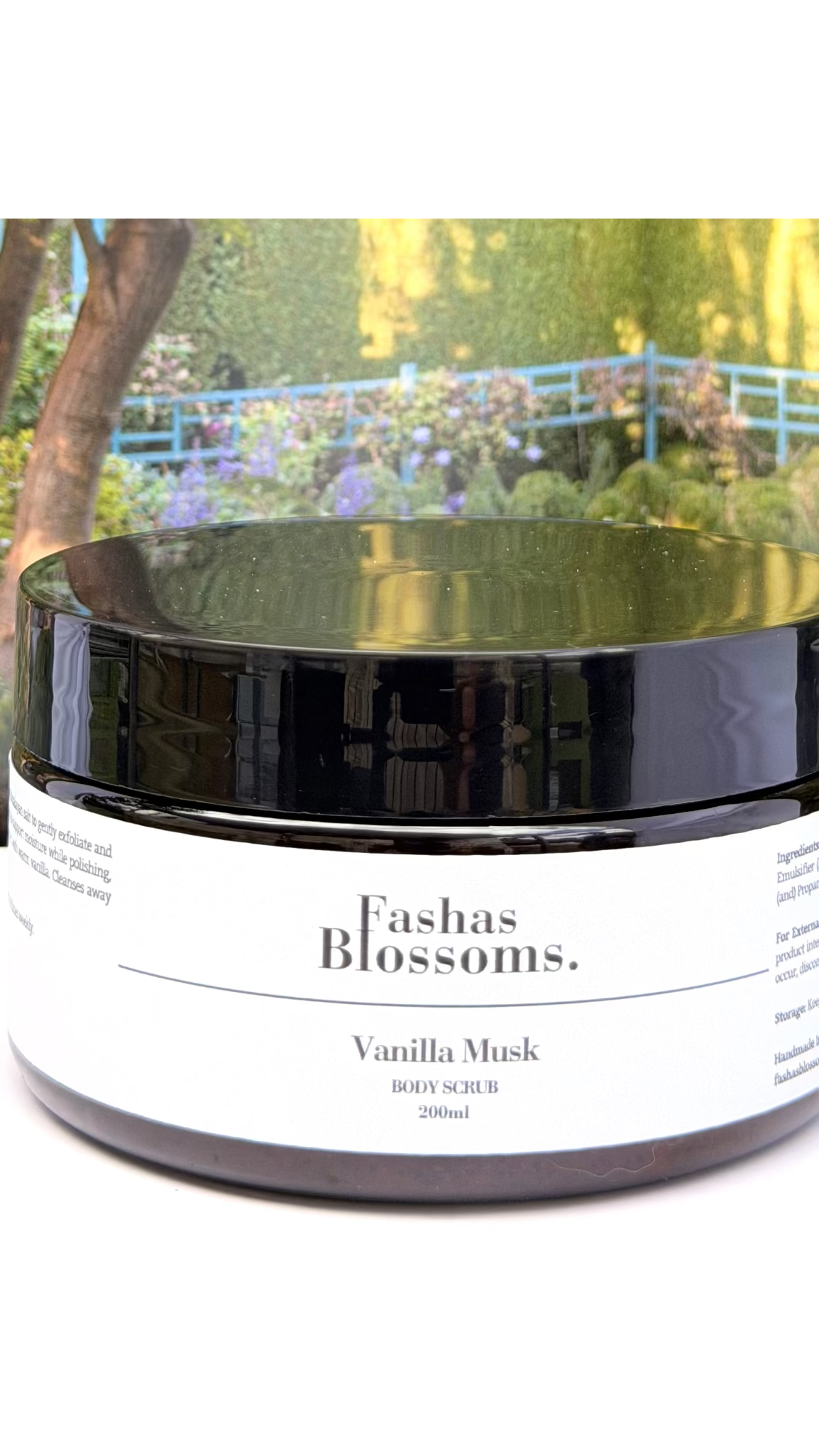 Jar of 'Fashas Blossoms Vanilla Musk' body scrub with a garden background